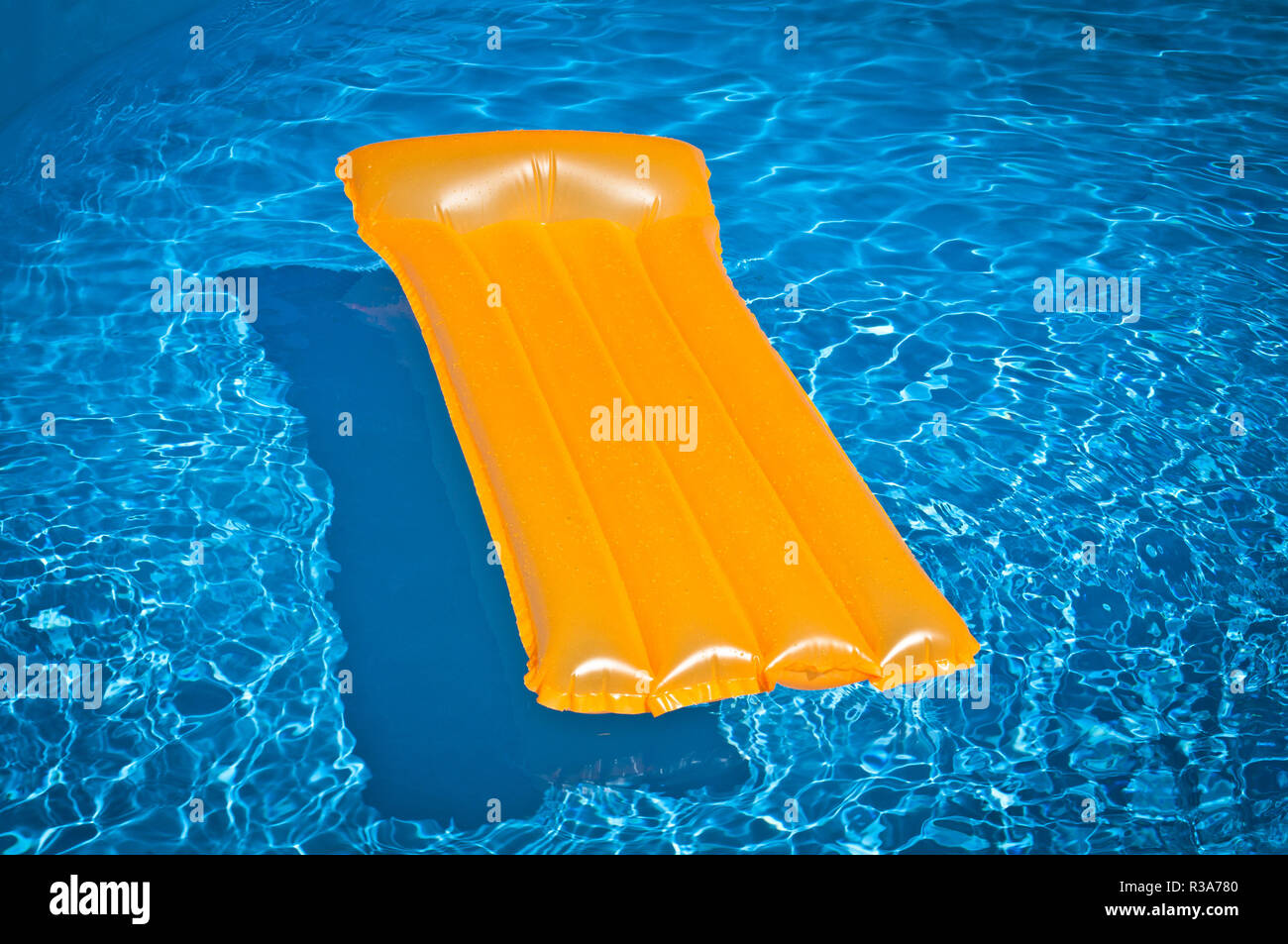 Matelas gonflable Orange flottant dans la piscine Banque D'Images