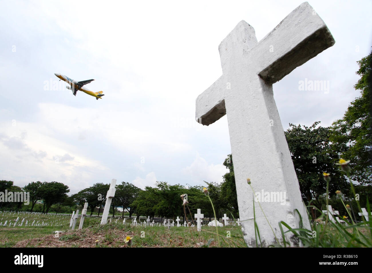 Un avion commercial est vus en vol au-dessus du cimetière des héros, également connu sous le nom de Libingan ng mga Bayani, à Taguig City, au sud de Manille, Philippines. Banque D'Images