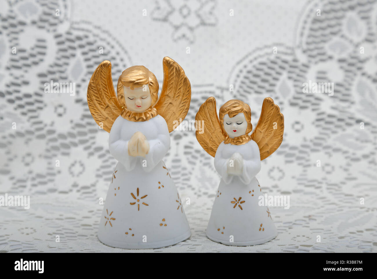 Deux petits anges en céramique blanche avec fond de dentelle blanc Banque D'Images