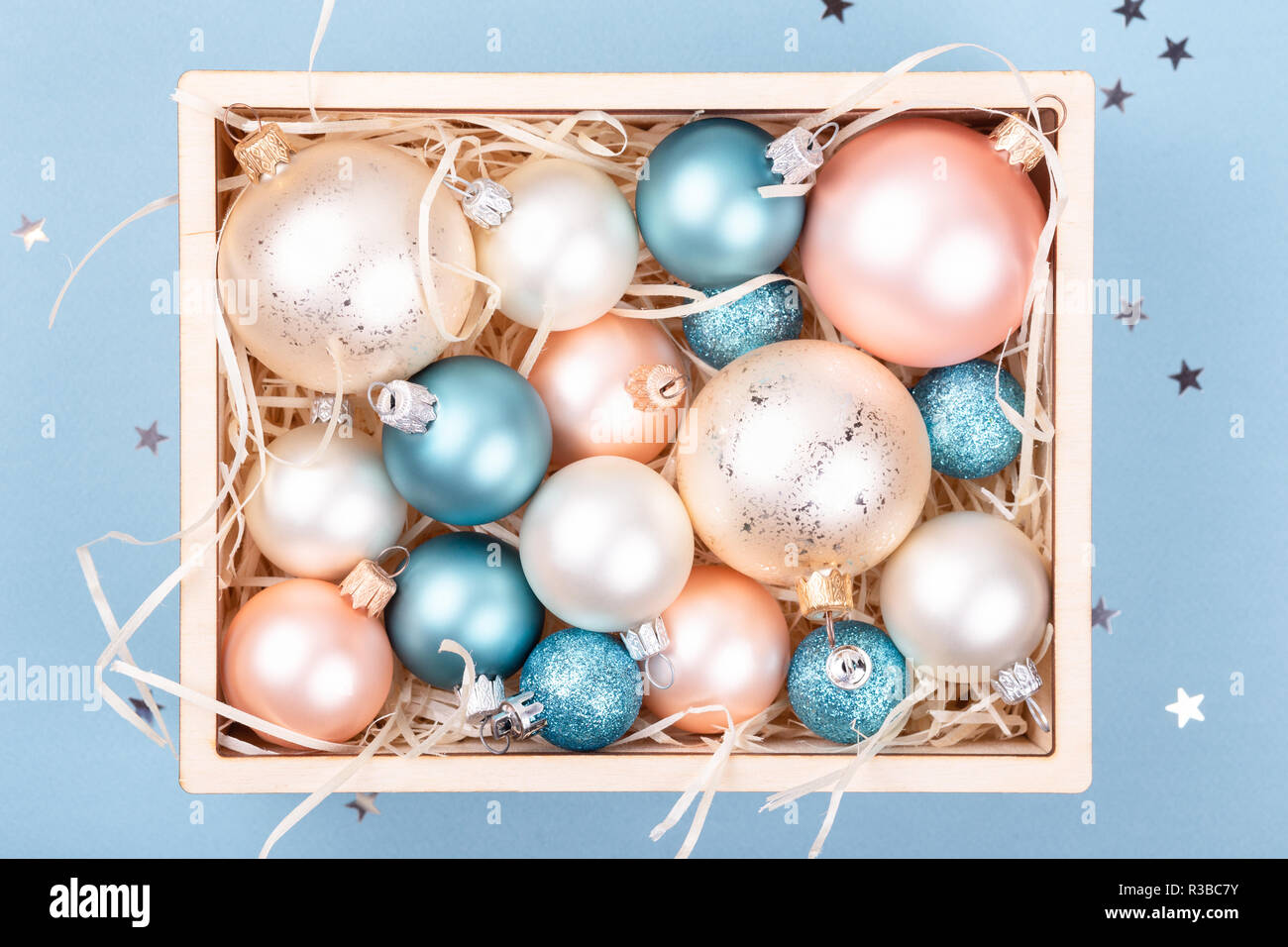 Boîte en bois avec des décorations de Noël sur fond bleu décoré de confettis. Vue d'en haut. Banque D'Images