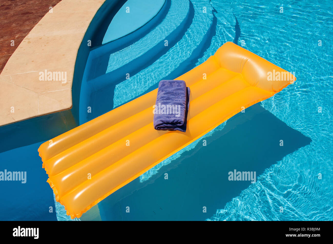 Matelas gonflable avec drap bleu flottant dans la piscine Banque D'Images