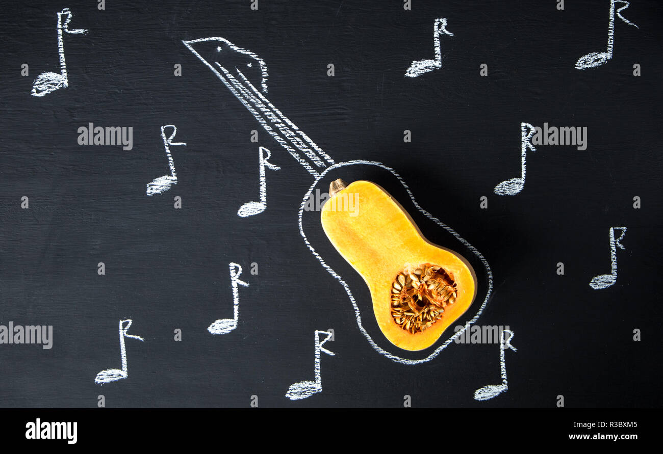 Moitié de matières organiques sous forme de citrouille à la guitare et une  photo de la guitare sur une ardoise noire, de pierre ou de béton  background.vue d'en haut Photo Stock -