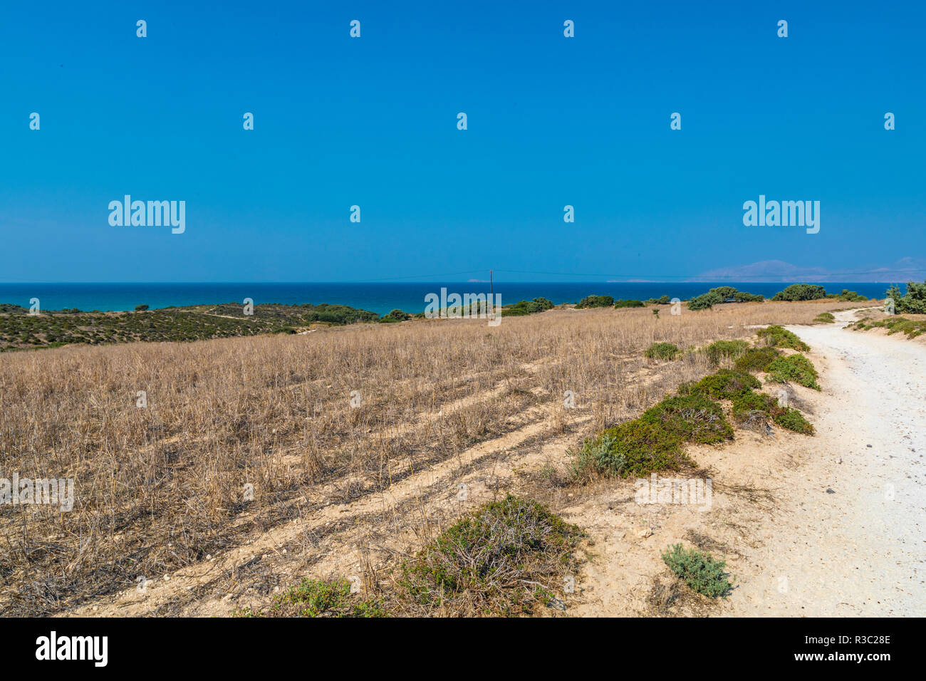 Paysage de barren lands grec sec représentant un champ et une route. Banque D'Images