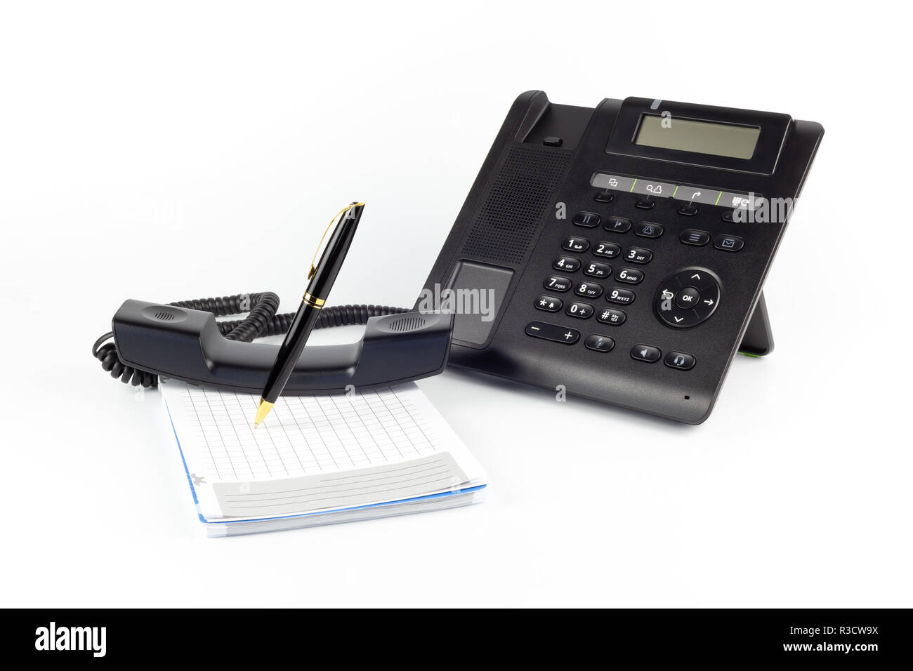 IP noir -téléphone, ordinateur portable et stylo pour écrire sur un fond blanc. Concept de poste de travail Banque D'Images