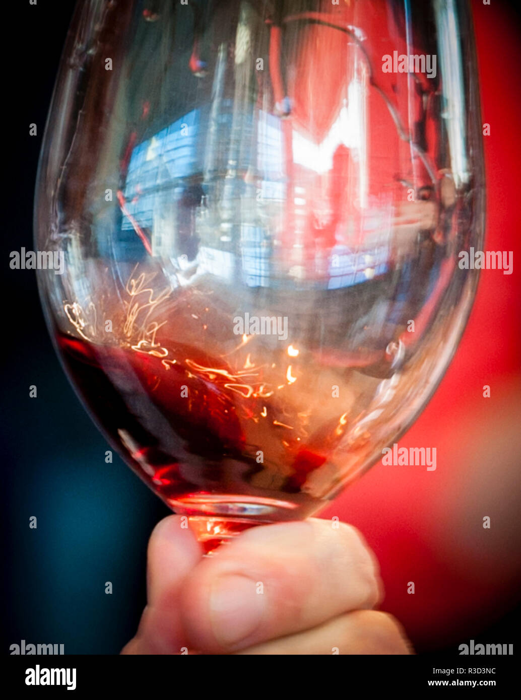 USA (Oregon, Portland. Un tourbillon de vin rouge dans le verre réfléchissant la lumière. Banque D'Images