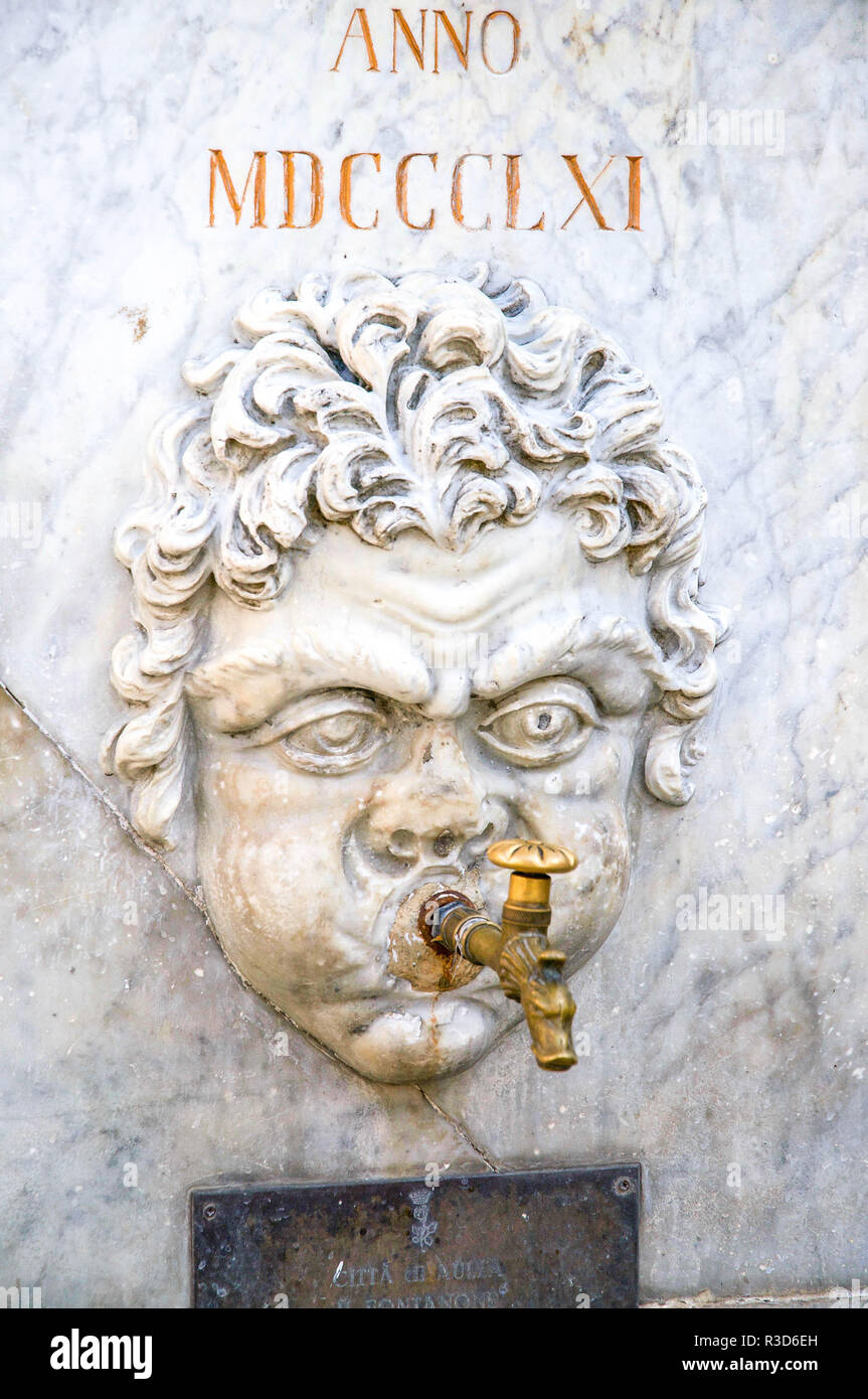 Tête sculptée de style romain à l'extérieur en fonction d'un robinet d'eau dans une piazza à Aulla, Toscane, Italie. Banque D'Images