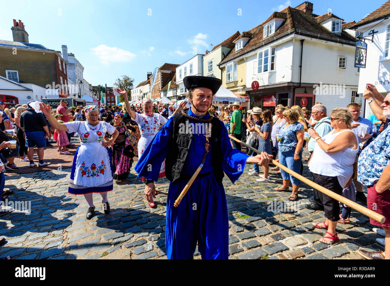 Faversham hop festival, Parade. Balaton danseurs hongrois, le plomb par l'homme en robe bleue, marche dans la rue bondée de spectateurs à regarder. Banque D'Images
