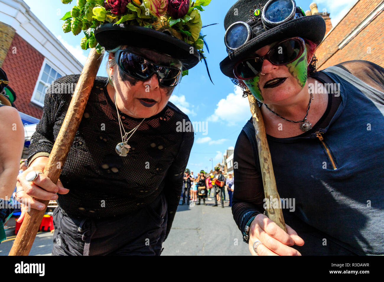 Faversham Hop Festival. Deux femmes folk dancers de Boxhill Bedlam Morris côté avec oeil noir masque peint sur leurs visages, se pencher pour regarder viewer. Banque D'Images