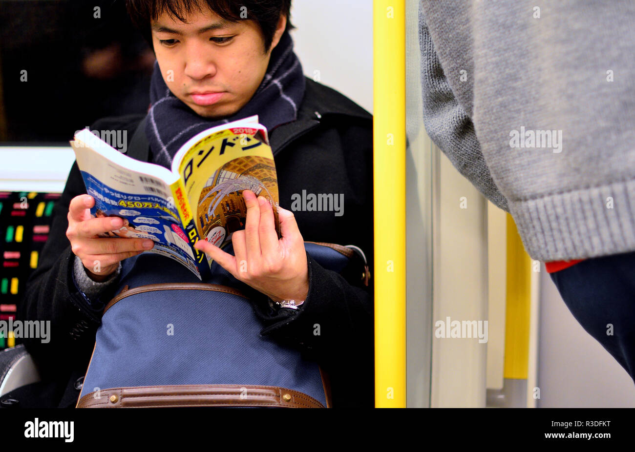 Jeune homme japonais Hentai la lecture d'un roman graphique sur un train de tube, Londres, Angleterre, Royaume-Uni. Banque D'Images