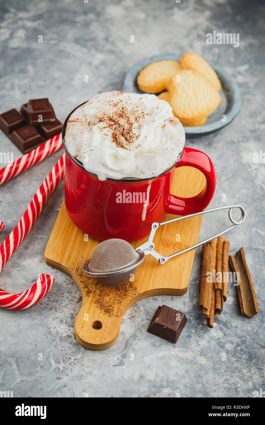 Tasse émaillée rouge Noël avec du chocolat chaud et crème fouettée, des bâtons de cannelle, d'anis étoile et de copieux shortbread cookies sucre et des cannes de bonbon sur Banque D'Images