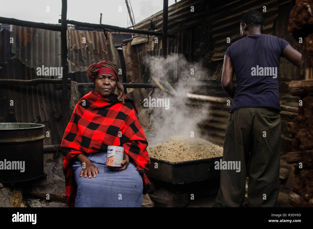 Un homme est vu la torréfaction mélange de sorgho afin de préparer l'alcool à Kibera. Pendant une longue période de temps, la plupart des femmes de Kibera ont été sous l'influence de l'alcool. Ne pas prendre en considération les effets secondaires, les femmes ici consommer pour différentes raisons, y compris la prise en charge du stress et d'oublier leurs problèmes de famille retour à l'accueil. Cela est dû à l'absence de suffisamment de possibilités d'emploi et de l'appui de leurs maris Le haut niveau de consommation d'alcool a entraîné une augmentation des taux de décès, de cécité, et risque de beaucoup de maladies dangereuses comme le cancer, l'hypertension, les accidents vasculaires cérébraux et les blessures traumatiques wit Banque D'Images