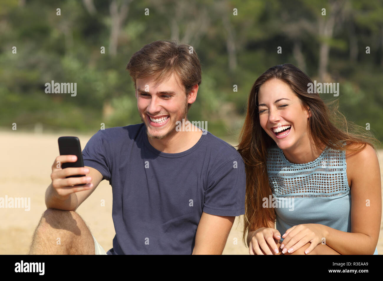 L'homme et la femme drôle de rire en regardant le téléphone intelligent Banque D'Images