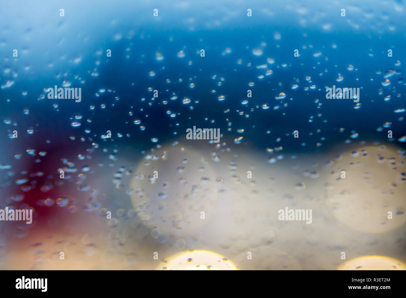 Gouttes d'eau de pluie dans la nuit ou le soir des lumières de rue sur fond de verre bleu. Bokeh rue Boke Lights Out de Focus. Abstraite automne Banque D'Images