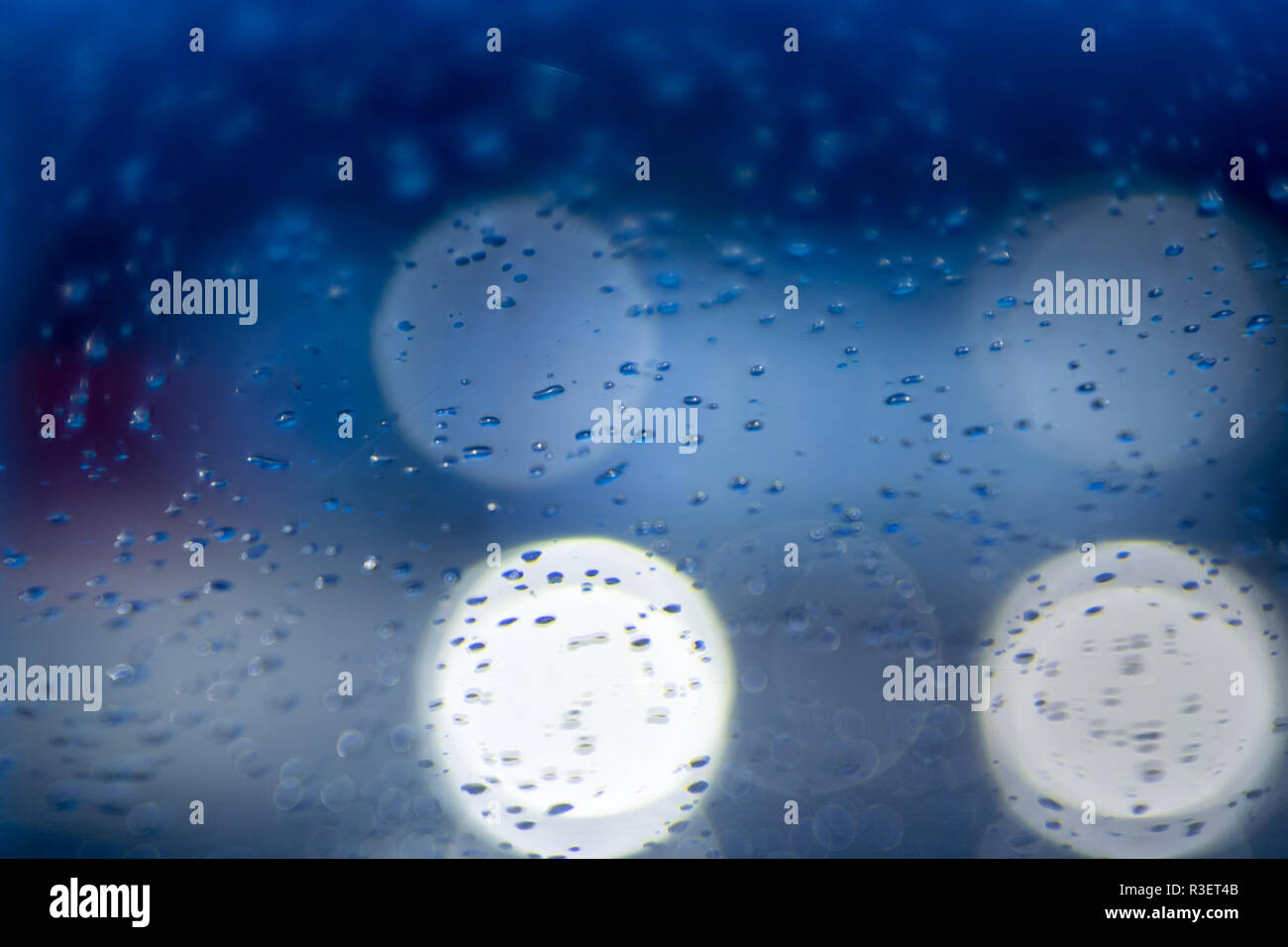 Gouttes d'eau de pluie dans la nuit ou le soir des lumières de rue sur fond de verre bleu. Bokeh rue Boke Lights Out de Focus. Abstraite automne Banque D'Images