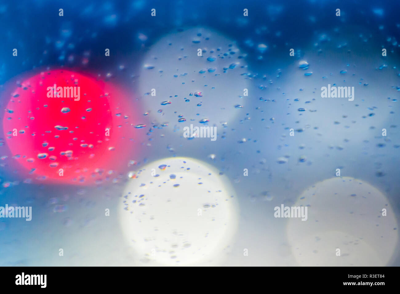 Gouttes d'eau de pluie dans la nuit ou le soir des lumières de rue sur fond de verre bleu. Bokeh rue Boke Lights Out de Focus. Abstraite automne Banque D'Images