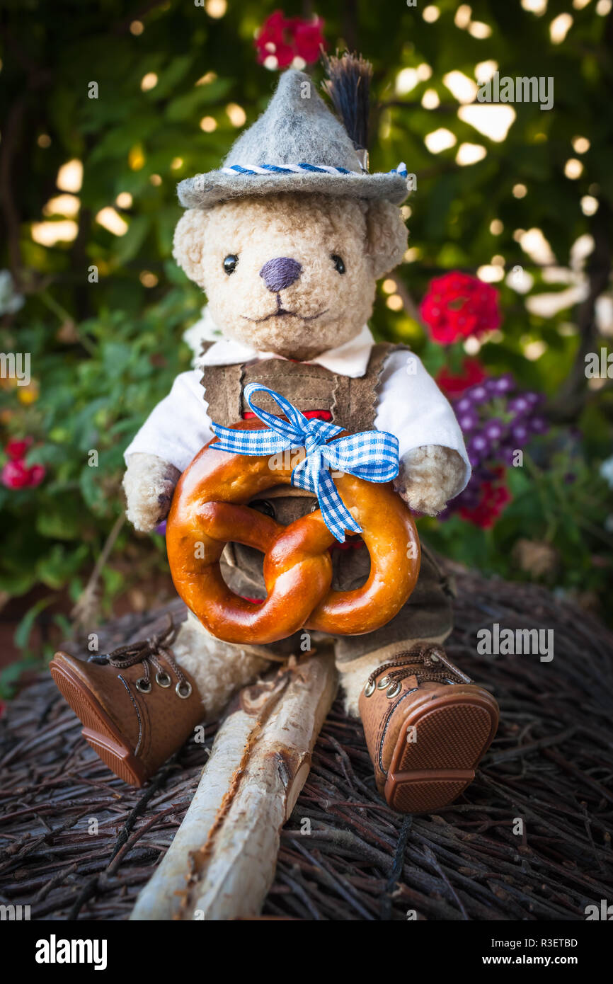 Smart, adorable ours en peluche costume traditionnel bavarois allemand  portant des pantalons de cuir et chapeau, délicieux bretzel avec ruban bleu  dans ses mains, assis Photo Stock - Alamy