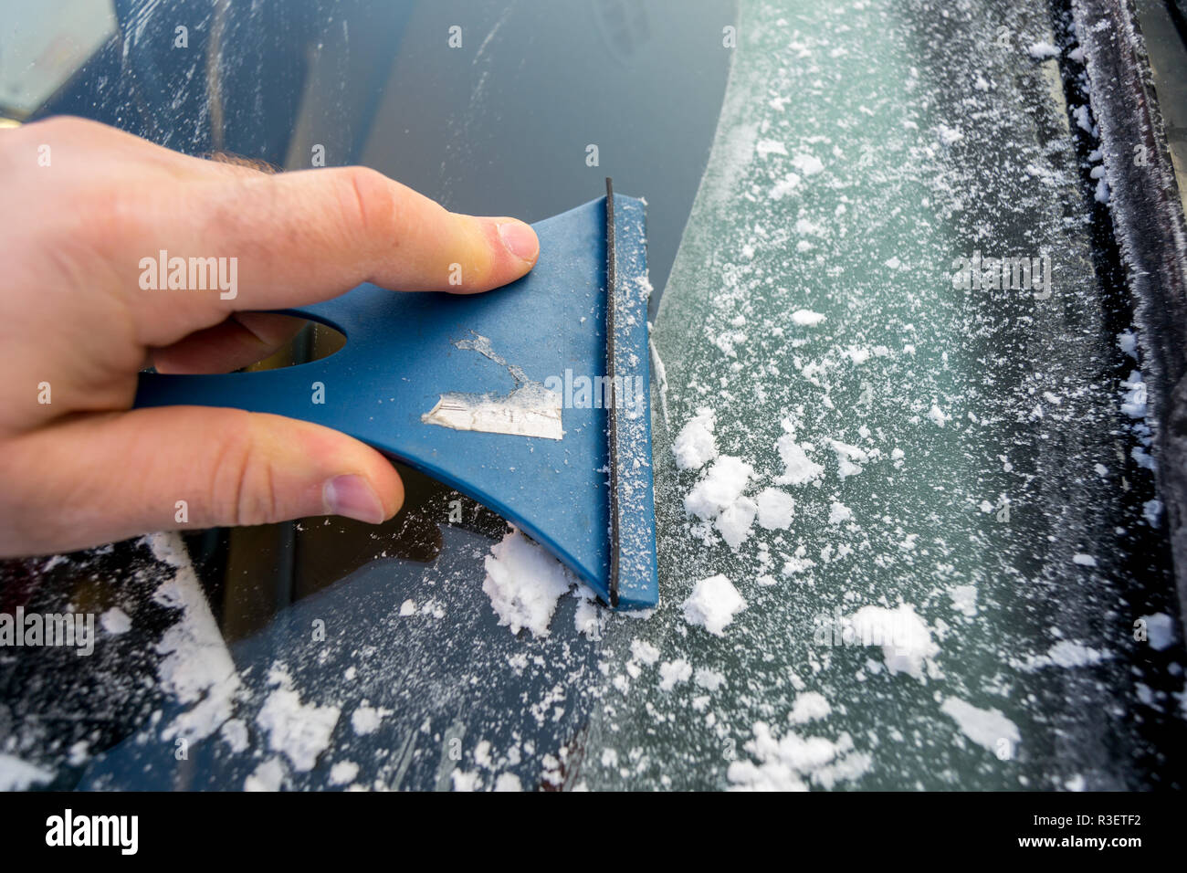Nettoyage extérieur de l'homme de la neige sur le pare-brise de sa voiture.Vue de l'extérieur de la voiture. Banque D'Images