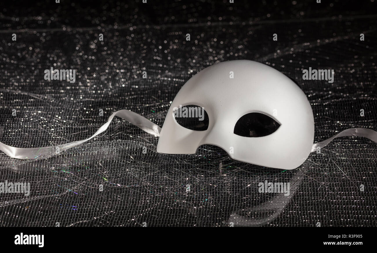 Masque de carnaval blanc, demi-visage sur fond brillant noir, vue rapprochée, copy space Banque D'Images
