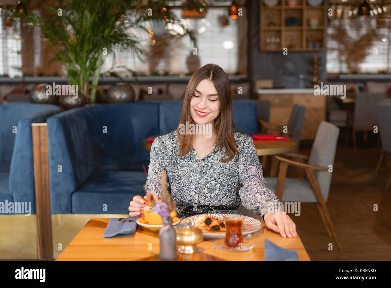 Une jeune femme a petit-déjeuner dans un café. Avec l'avoine et caramel salé pruneaux, dans l'original de servir. Le petit-déjeuner, agréable matinée, le début de la journée de travail. femme sourire Banque D'Images