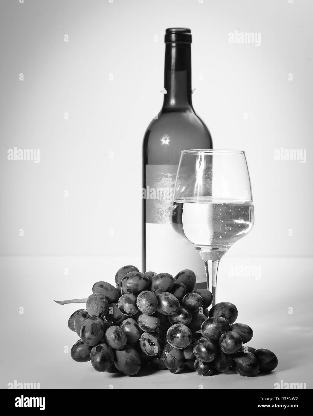 Un verre de vin blanc, une grappe de raisins, une bouteille ouverte. Arrière-plan blanc. Banque D'Images