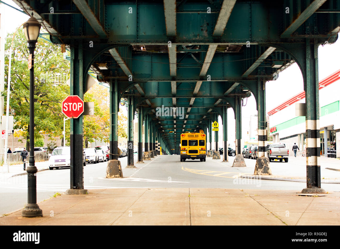 Un autobus scolaire est passé sous le pont de chemin de fer dans le Bronx, New York City, USA. Banque D'Images