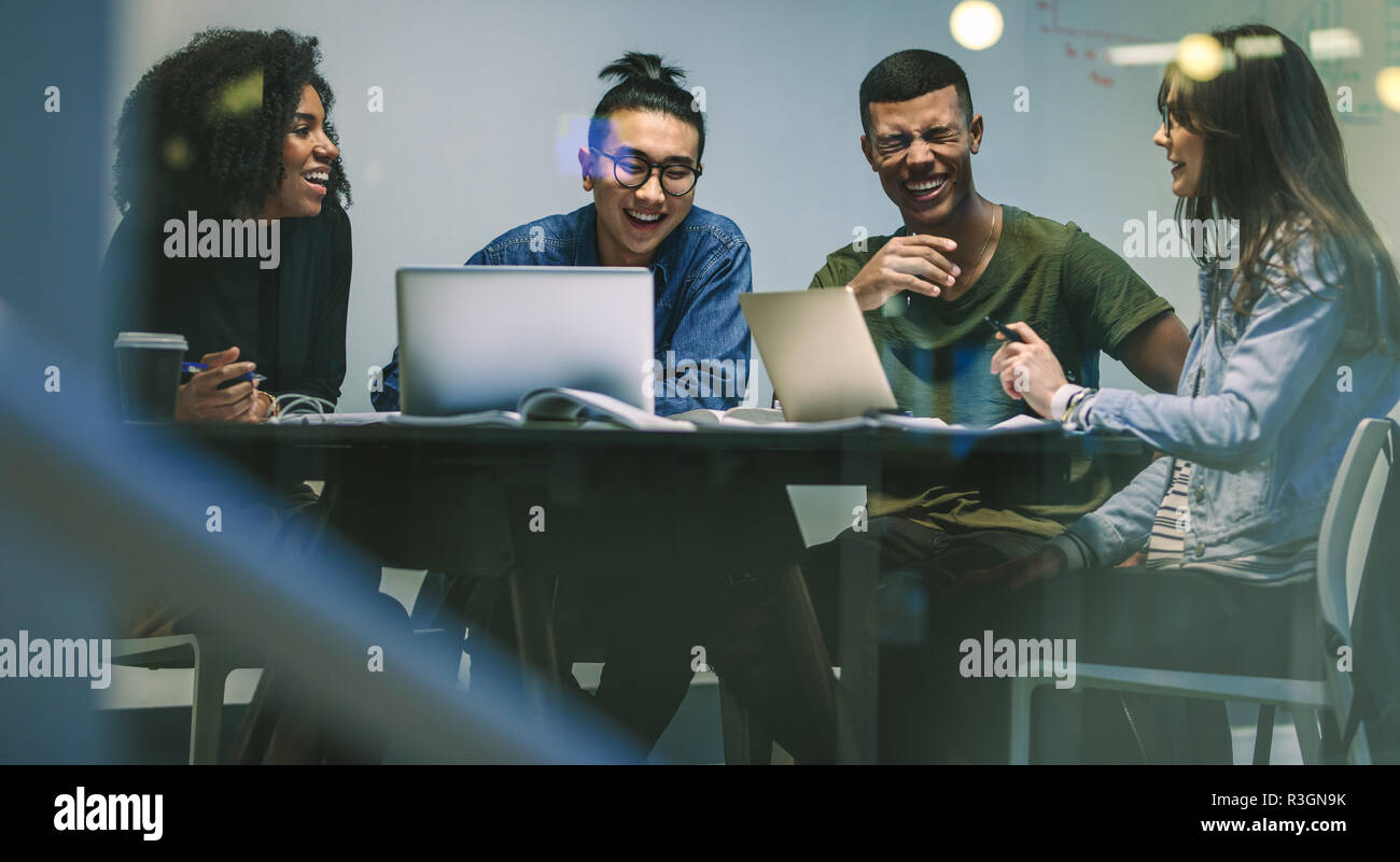 Smiling groupe d'élèves dans un college library assis à une table avec leurs ordinateurs portables. Multi-ethnic hommes et femmes au campus de l'université. Banque D'Images