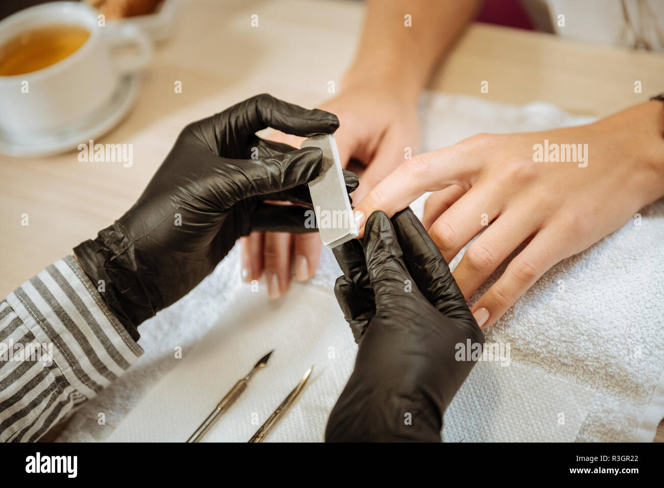 Artiste de l'ongle noir portant des gants à l'aide d'instruments