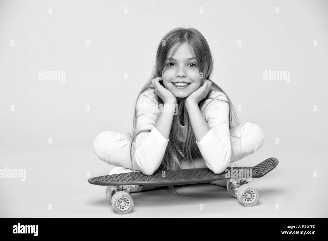 Skateboard kid se coucher sur le plancher sur fond rose. Patineur Enfant souriant de longboard. Petite fille sourire avec skate board. Vie active et de la petite enfance Banque D'Images