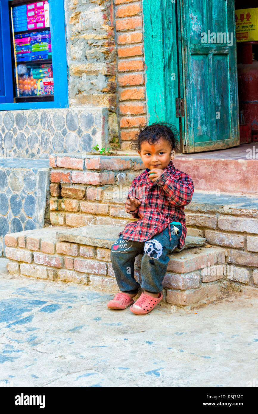 Garçon assis sur l'escalier népalais, Bandipur, Tanahun district, Népal Banque D'Images