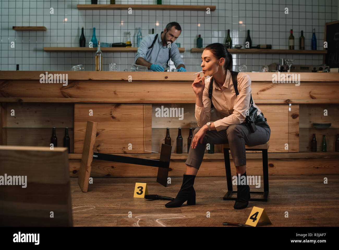 Portrait de femme assise à fumer détective scène de crime avec collègue travaillant derrière Banque D'Images