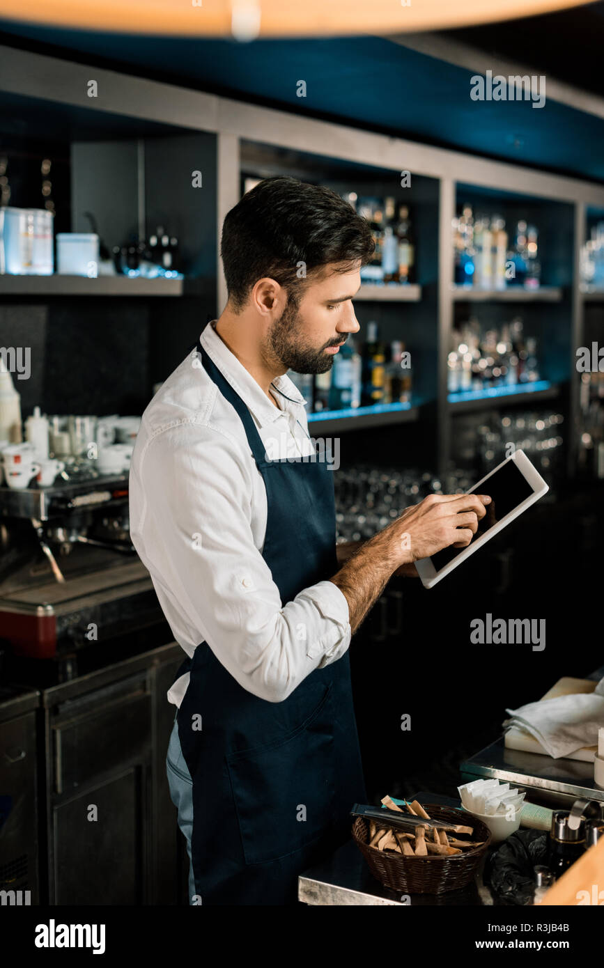 Tablier Barman debout dans with digital tablet in bar Banque D'Images