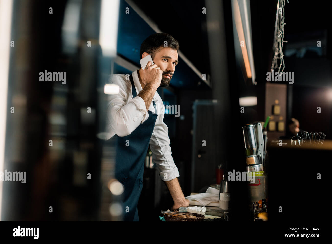 Handsome man talking on smartphone in bar Banque D'Images