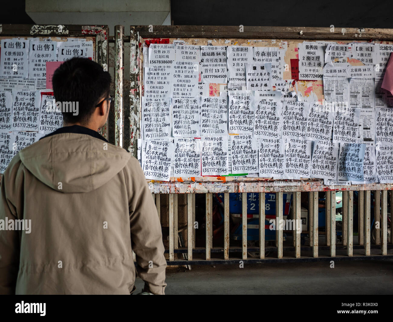 La lecture de l'homme chinois annonce immobilière locale et les circulaires d'appartements à vendre dans les environs de domaine. Ville de Liuzhou, Guangxi, Chine. Banque D'Images