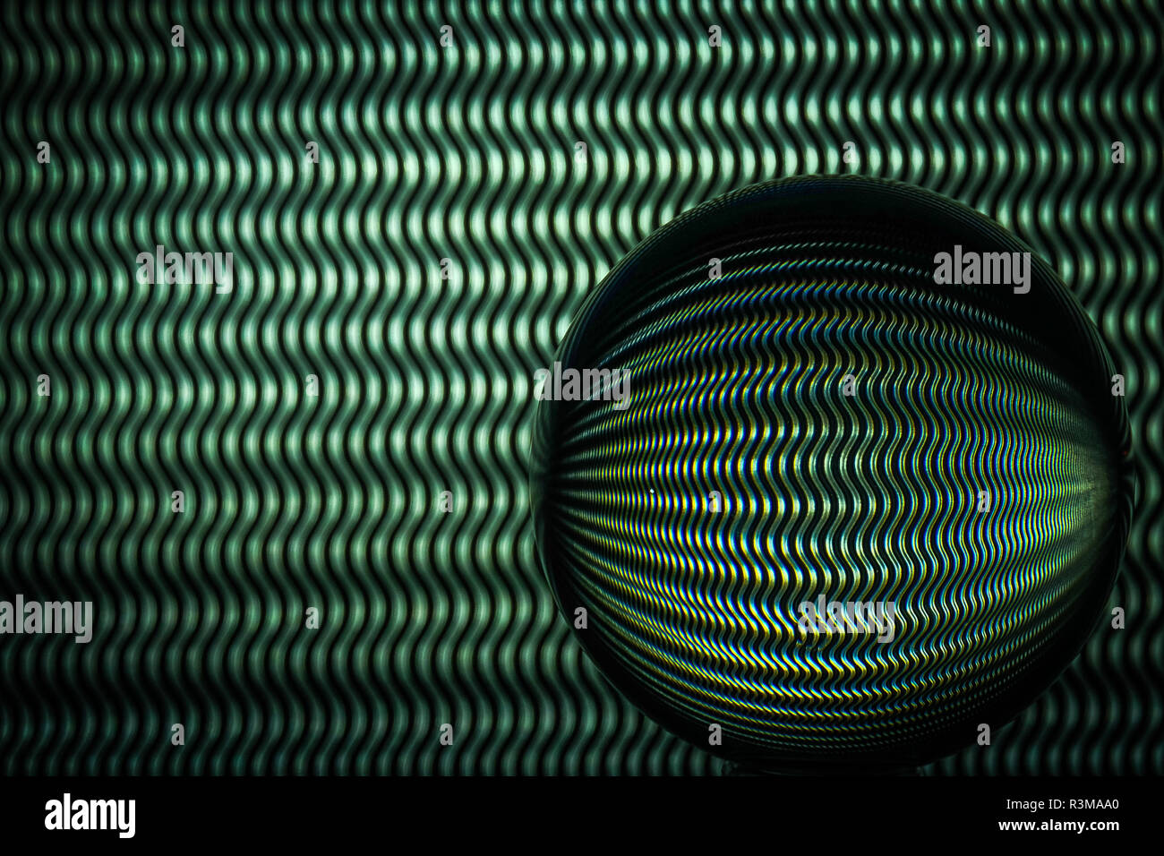 Des lignes ondulées vert et noir reflétant dans une sphère de verre Banque D'Images