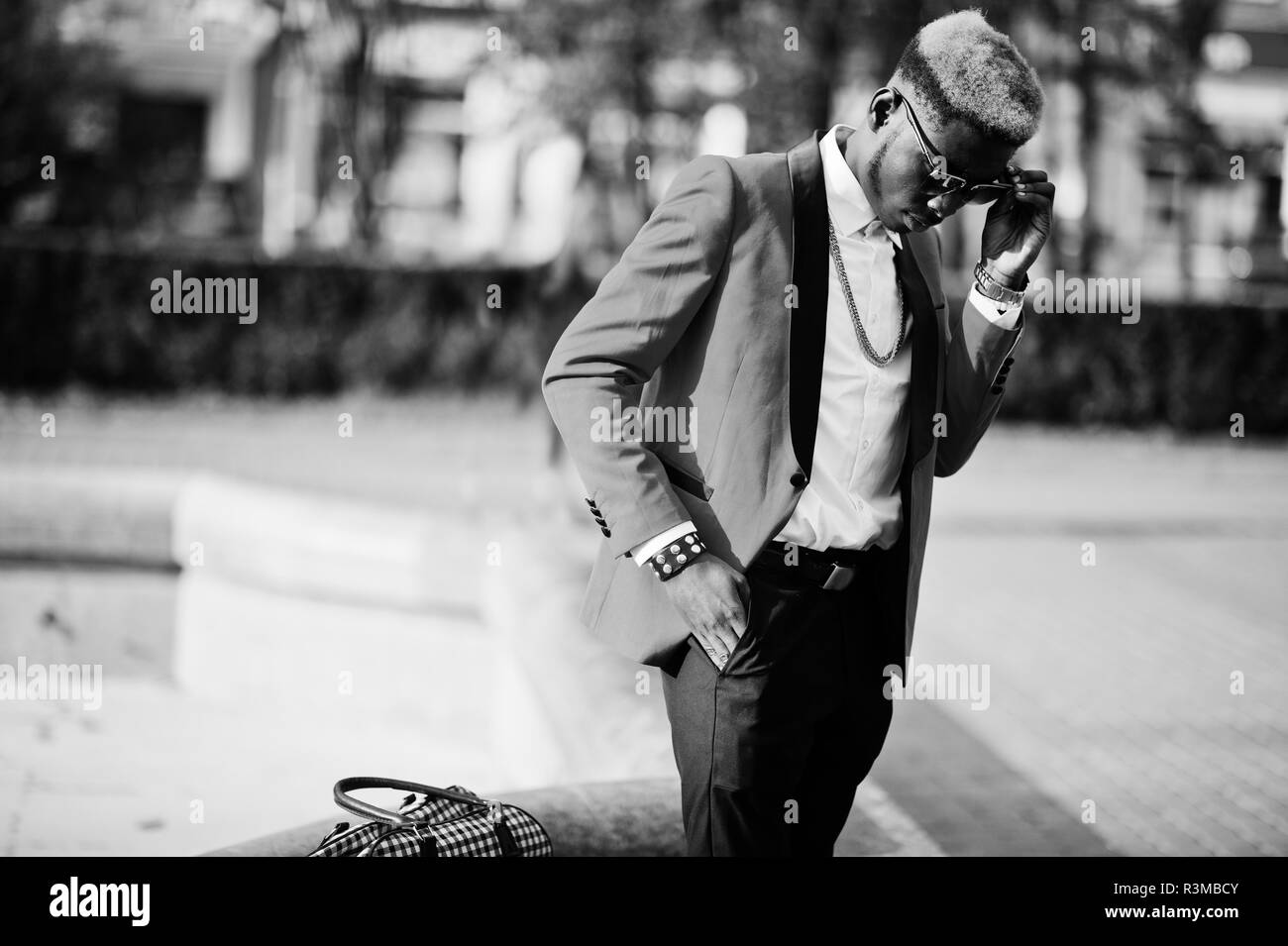 Fashion african american man modèle au costume rouge, avec des cheveux et de sacs à main faits saillants posés au niveau de la rue. Banque D'Images
