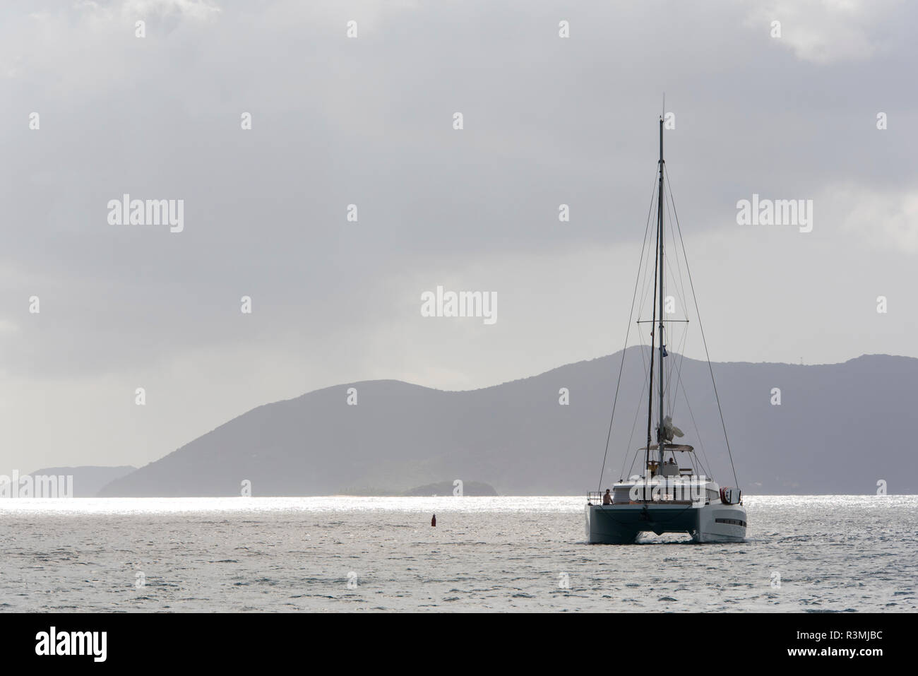 UK, British Virgin Islands, Catamaran navigue ciel gris reflétait calme mer des Caraïbes Banque D'Images