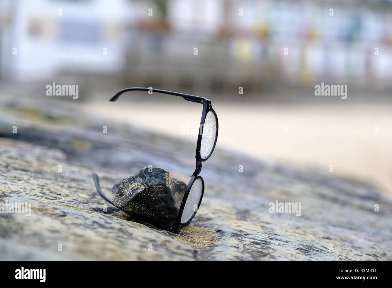 Une paire de lunettes perdue sur la plage sont pondérées de gauche vers le bas sur un rocher dans l'espoir que les propriétaires peuvent revenir et de les trouver. Banque D'Images