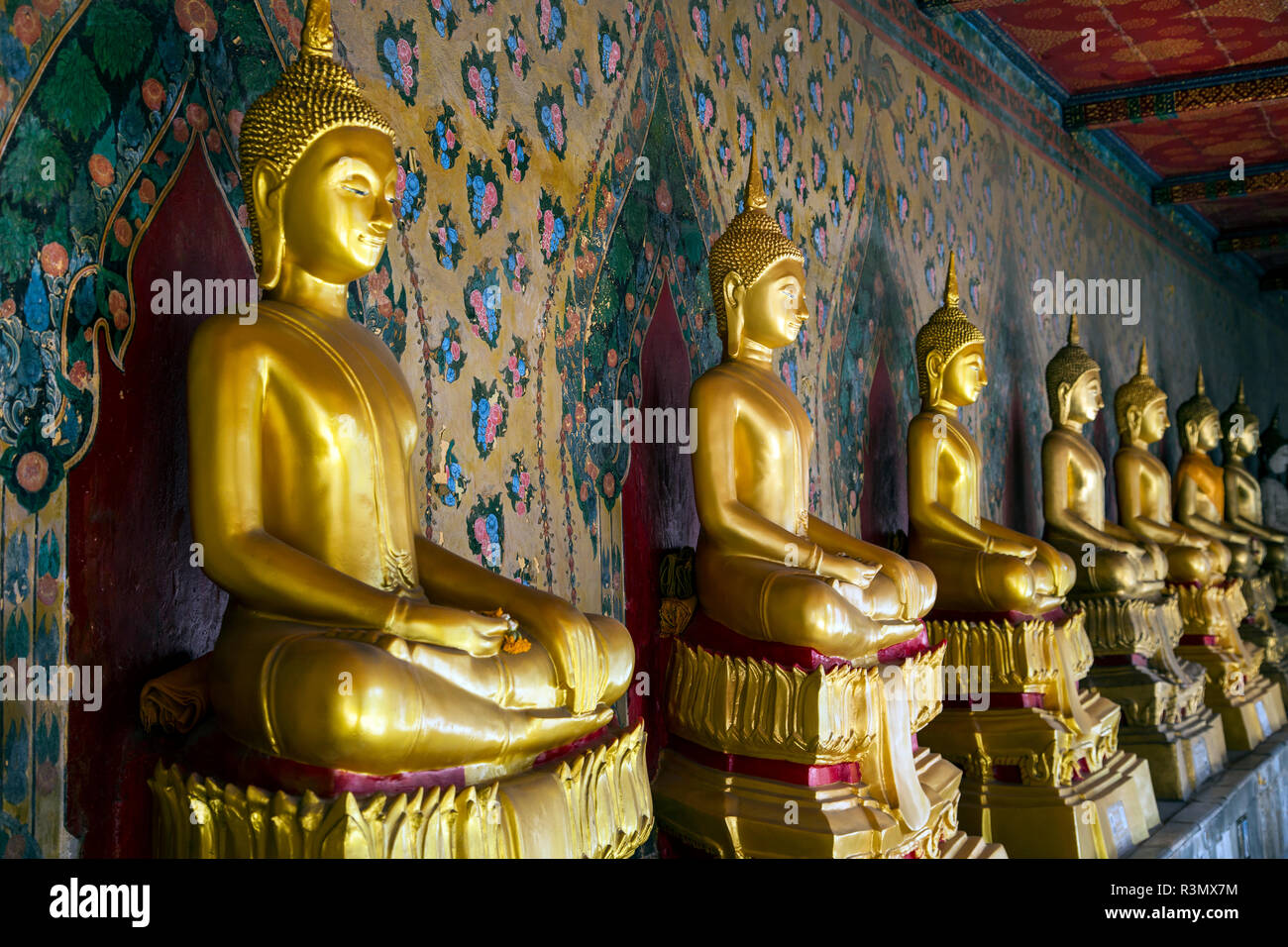 Bangkok, Thaïlande. Wat Arun, le Temple de l'aube, assis et méditant golden Buddha statues dans une rangée dans la galerie du bot Banque D'Images