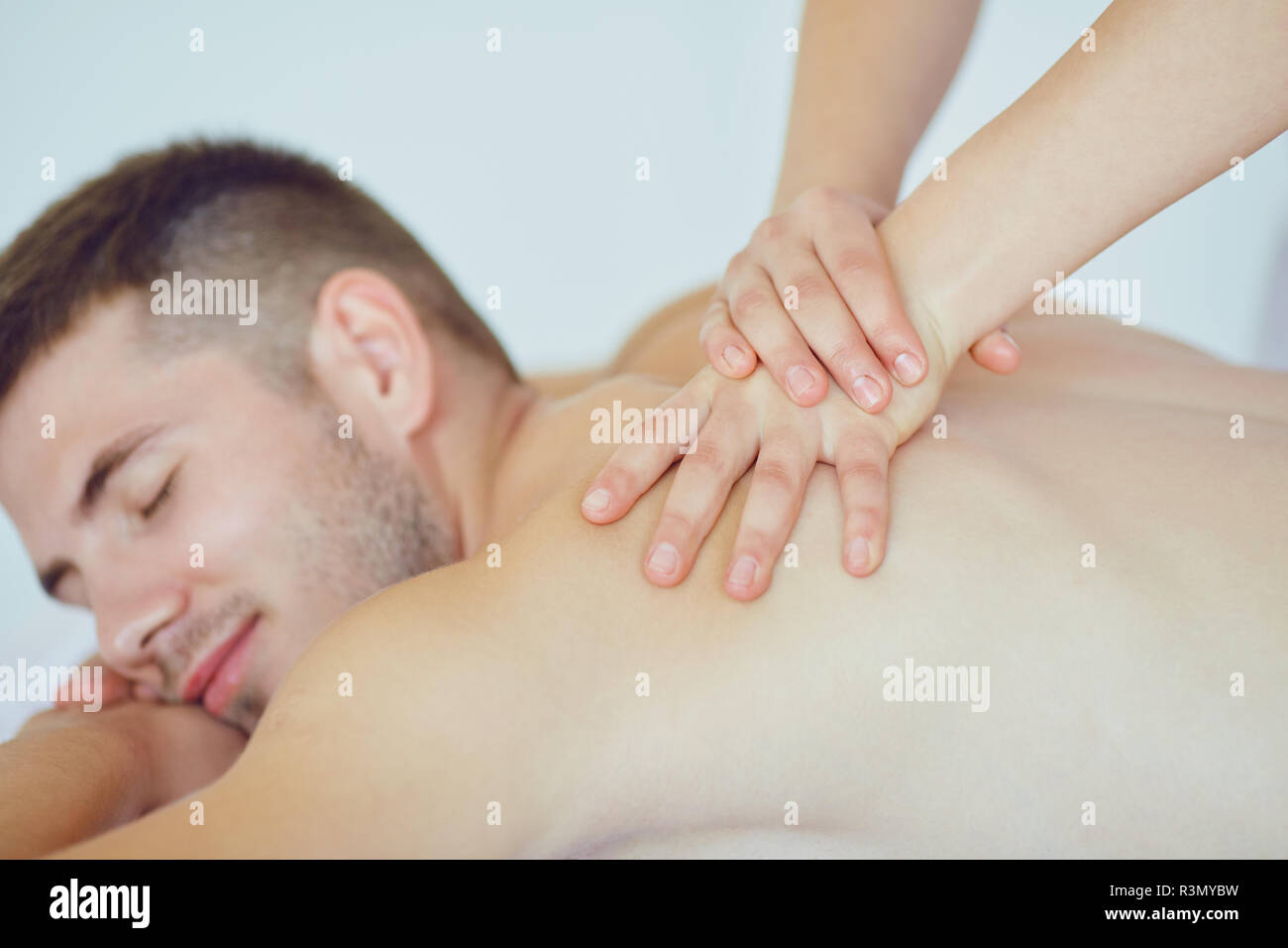 Massage dos pour un homme allongé sur la table dans le salon spa Banque D'Images