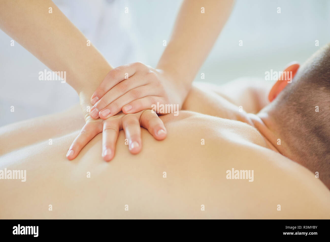 Une masseuse massage n à un homme allongé sur une table. Banque D'Images