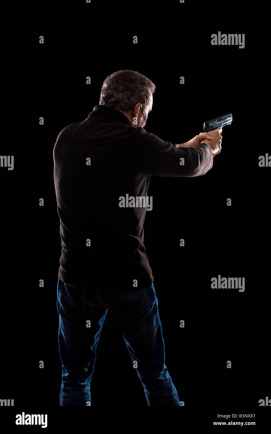 Silhouette d'un homme avec une arme à feu Banque D'Images