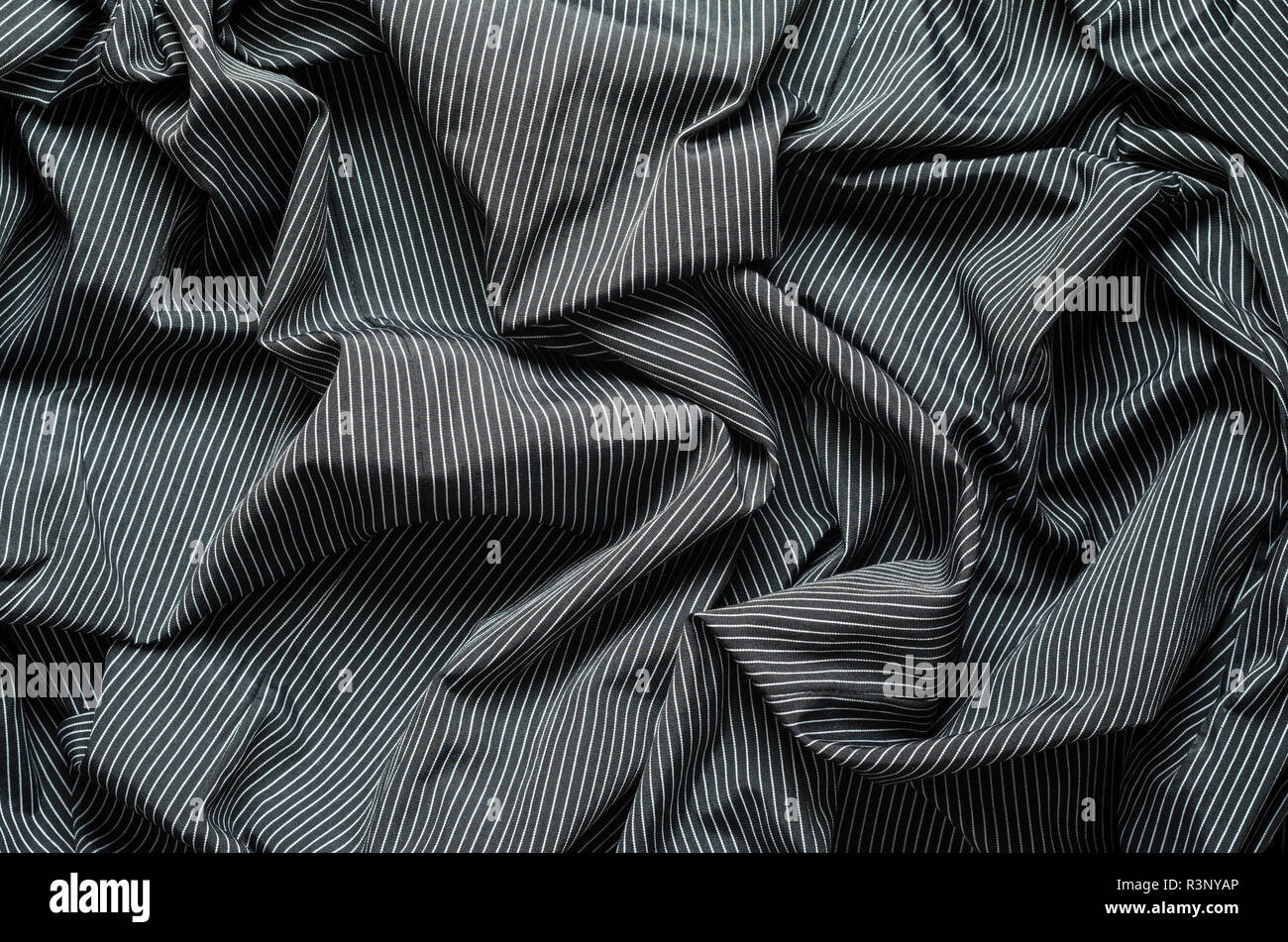 Texture ridée de tissu noir avec des lignes verticales blanches. Toile de fond textile Crumplet Banque D'Images
