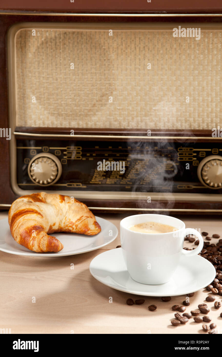 Écouter la radio pendant le petit-déjeuner avec café croissant Photo Stock  - Alamy
