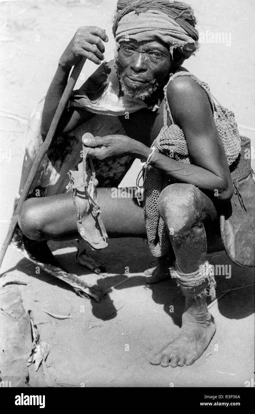 Cameroun tribesman tenant une pièce de monnaie et usé chaussures 1950 Banque D'Images