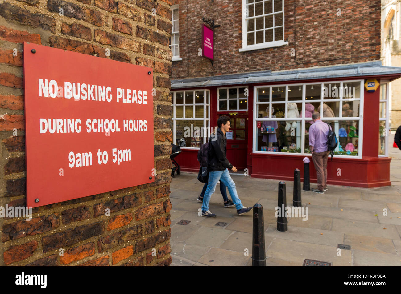Les gens passer signe rouge attaché à un mur de brique extérieur, demande polie de dire "non merci buskers pendant les heures d'école' - York, Yorkshire, Angleterre, Royaume-Uni. Banque D'Images