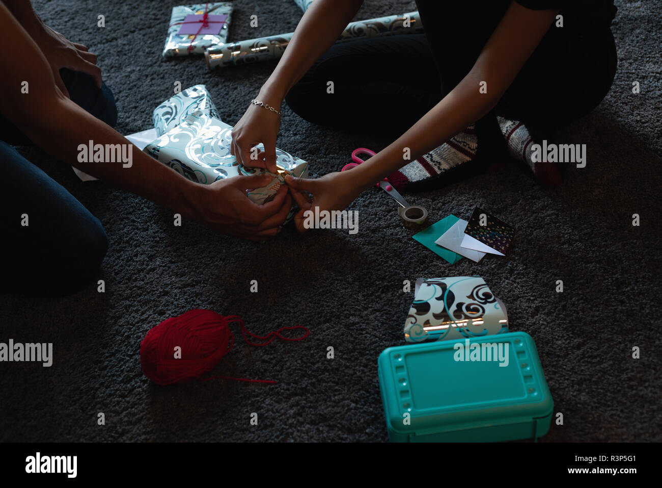 Emballage boîte-cadeau couple sur le plancher à la maison Banque D'Images