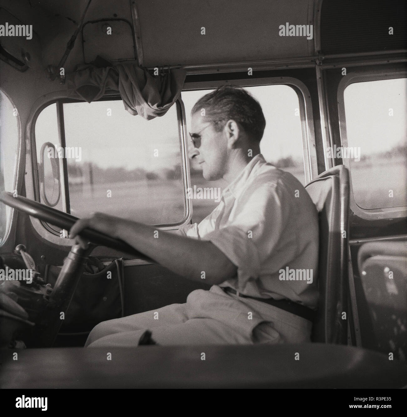 Années 1950, historique, un chauffeur de car homme assis avec ses mains sur le volant de ses transports, de l'Europe. Banque D'Images