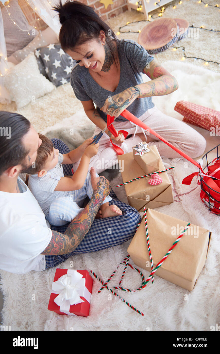 Boy opening Christmas present avec ses parents au lit Banque D'Images