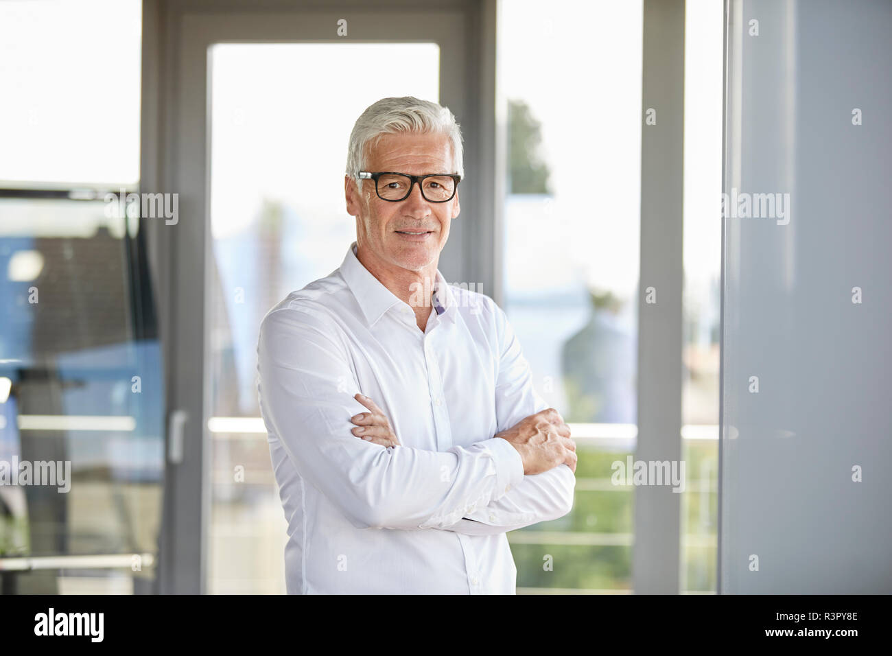 Confident businessman standing in office, with arms crossed Banque D'Images