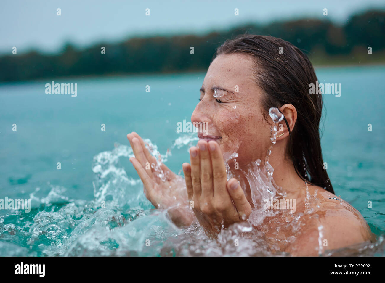 Jeune femme dans le lac de baignade avec de l'eau éclaboussant Banque D'Images